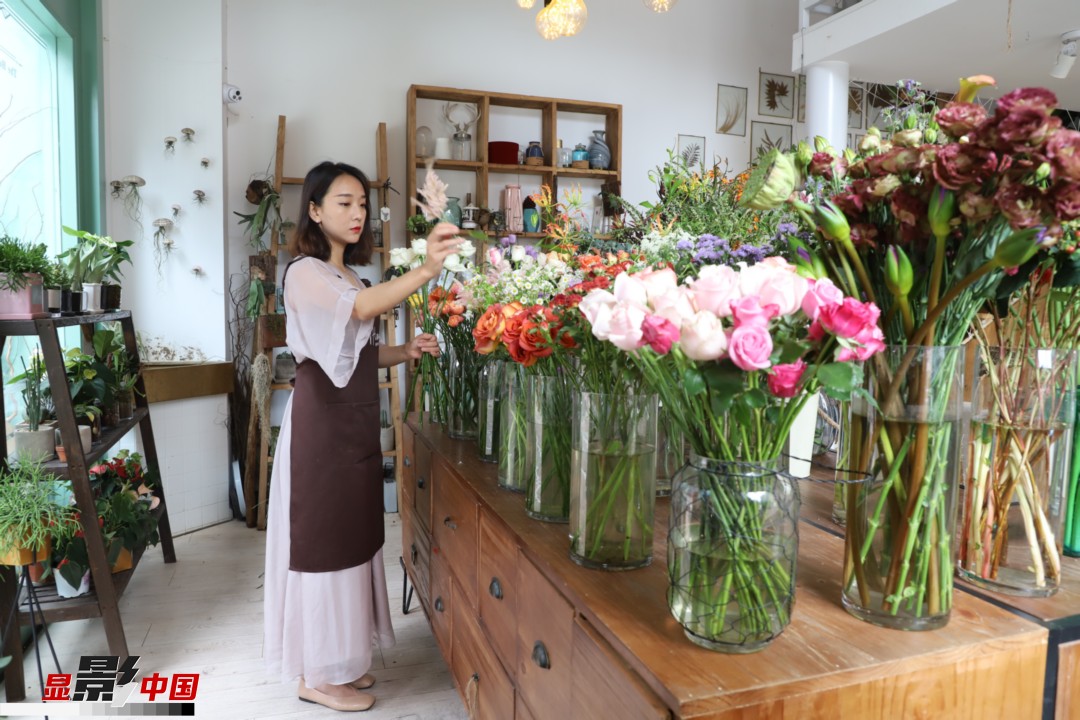王黎媛是一名河南姑娘，在昆明念完大學(xué)后，就再也舍不下春城的藍(lán)天陽光、青山碧水，更舍不下這里的四時繁花，于是就干脆留了下來，成了一名媒體人。2017年的時候又毅然辭去工作，創(chuàng)業(yè)開起了花店，成了都市里的一名“花房姑娘”。圖為王黎媛在自己的花店中整理鮮花。新華網(wǎng) 周亞平/攝 念新洪/文